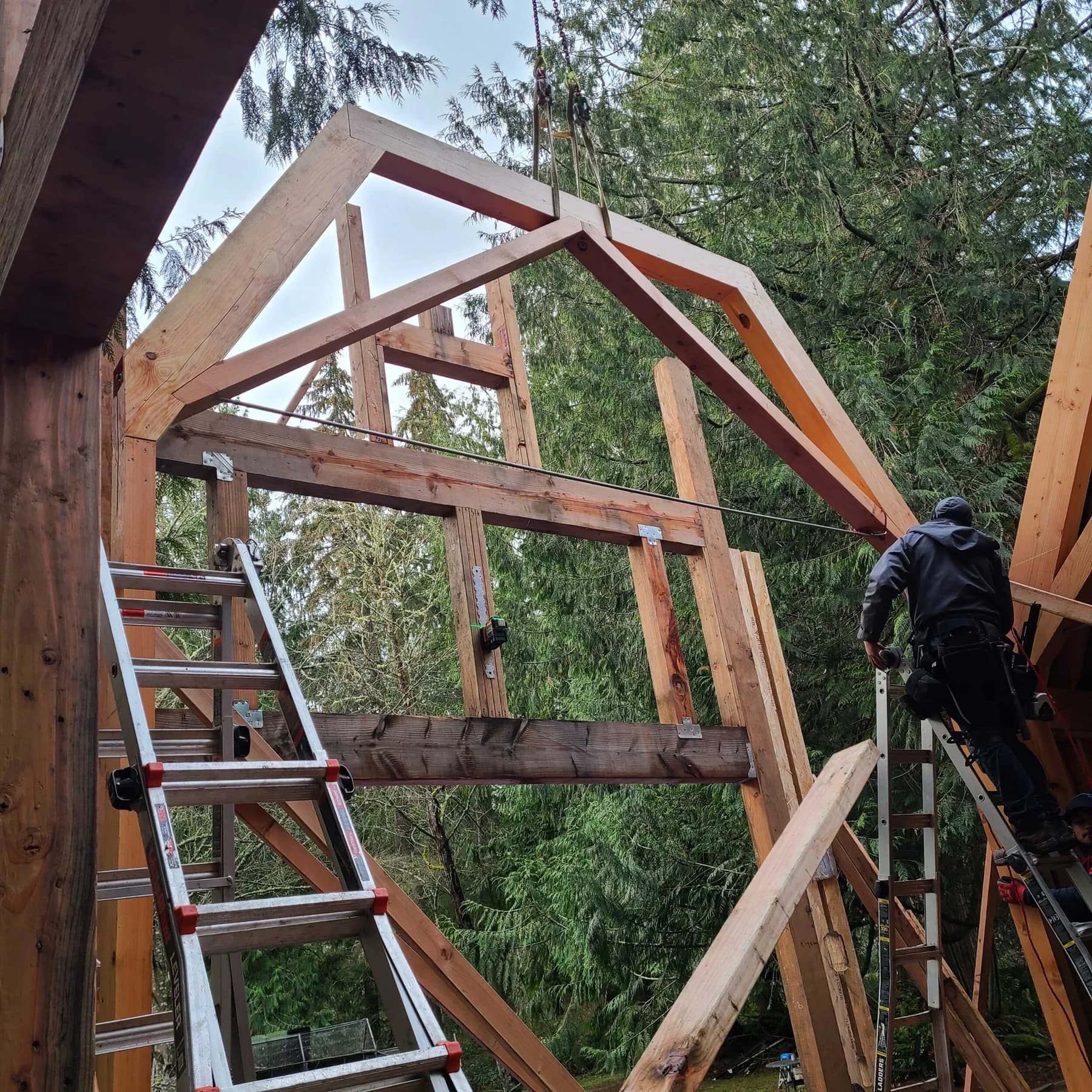 Structural Framing — A worker positioning a timber roof frame above exposed wall framing