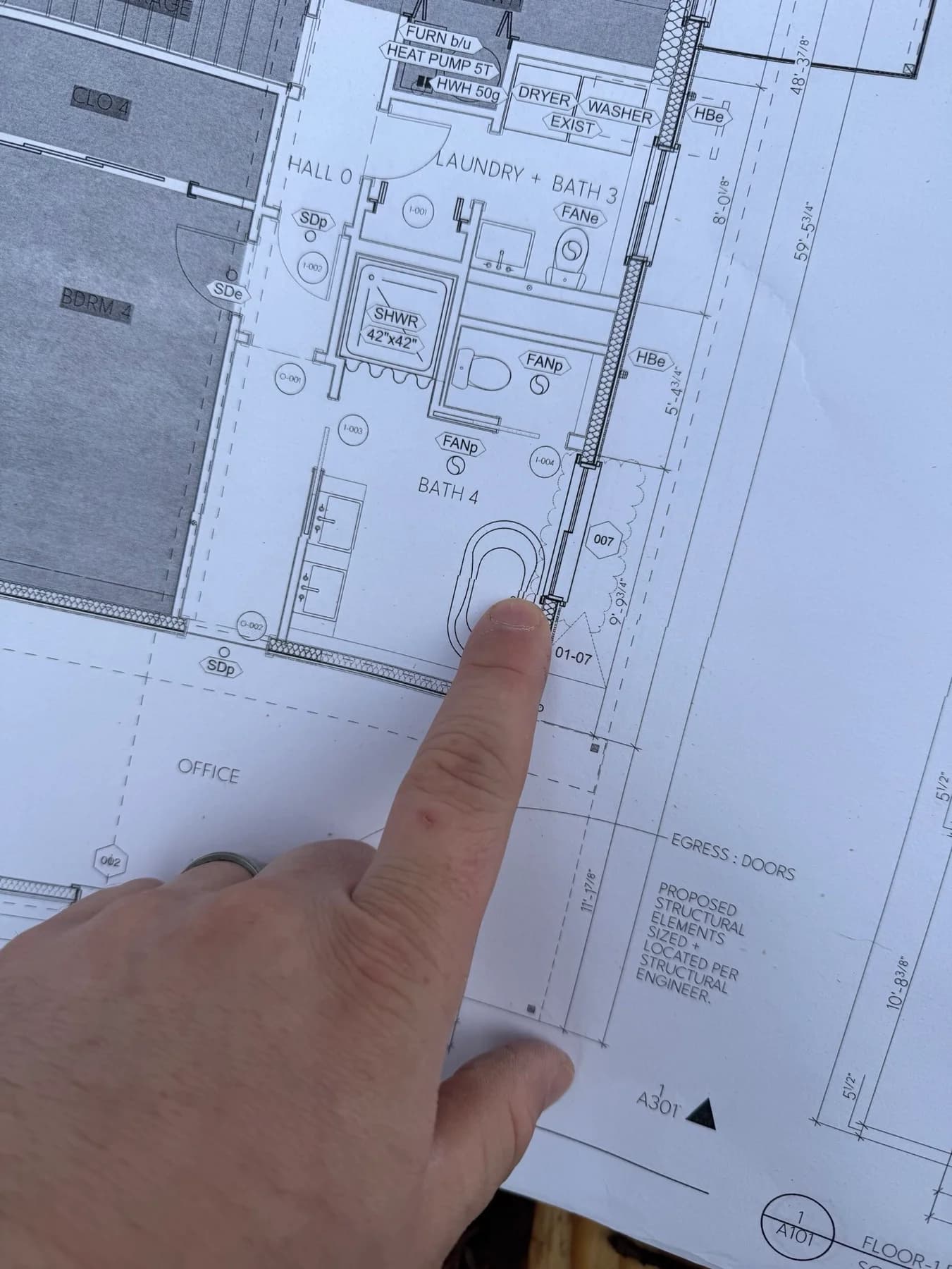 Feasibility planning — A hand reviewing room layouts and dimensions on a residential floor plan