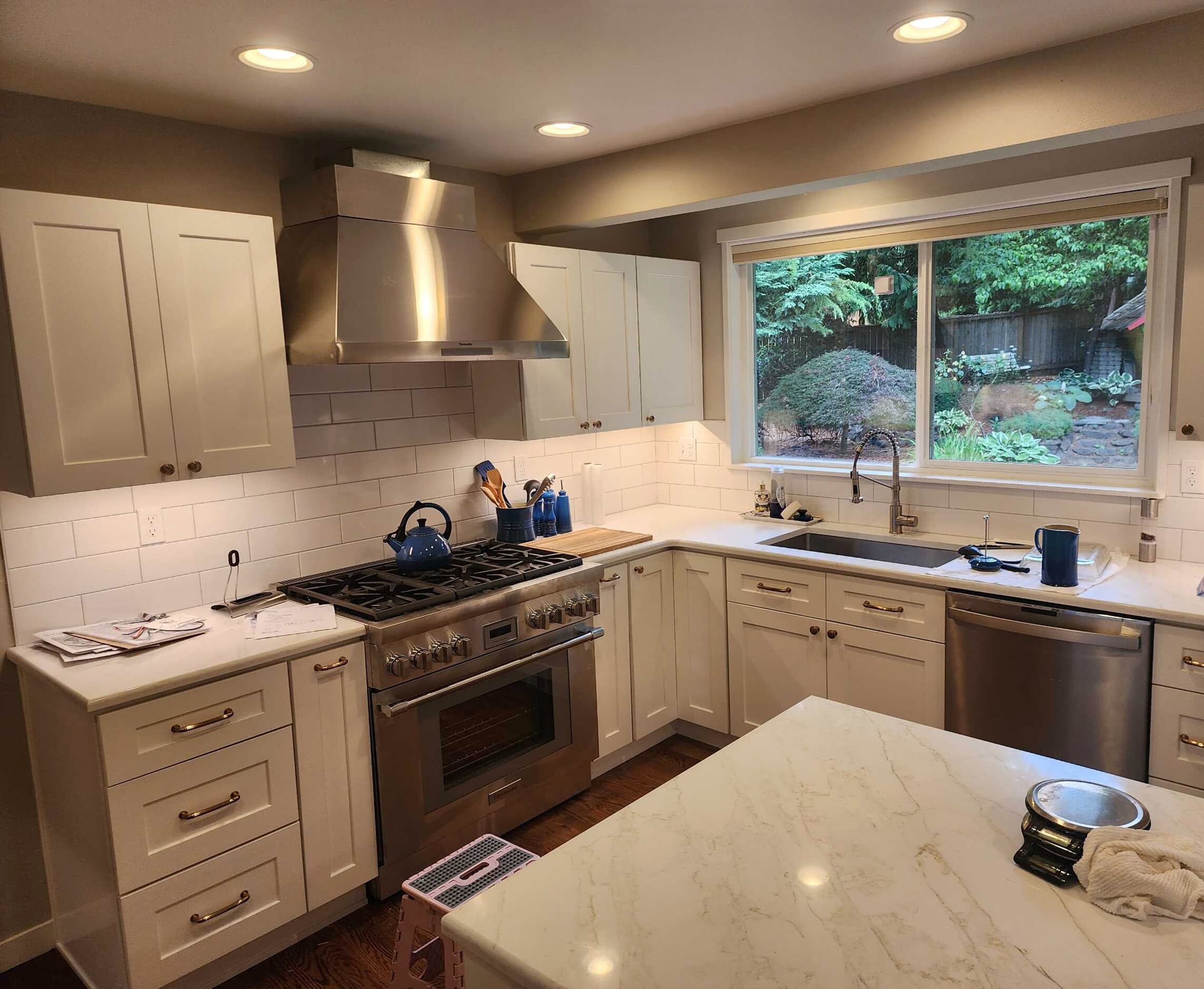 Project Evidence — Kitchen remodel with white shaker cabinets, stainless range hood, and marble-look island