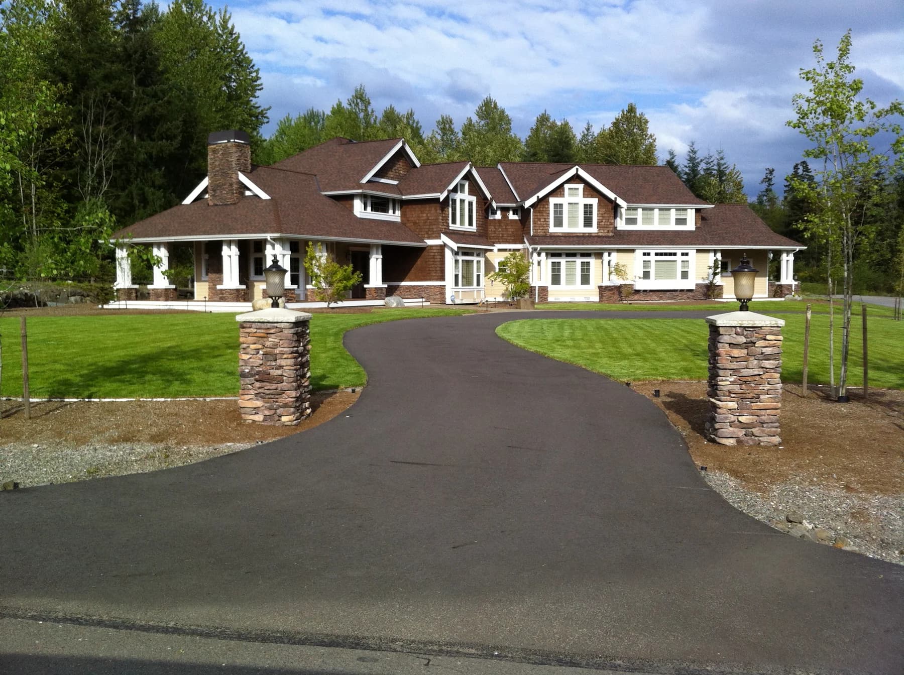 Custom Home — Completed two-story custom home with shingle siding, white trim, a wraparound porch, and landscaped grounds