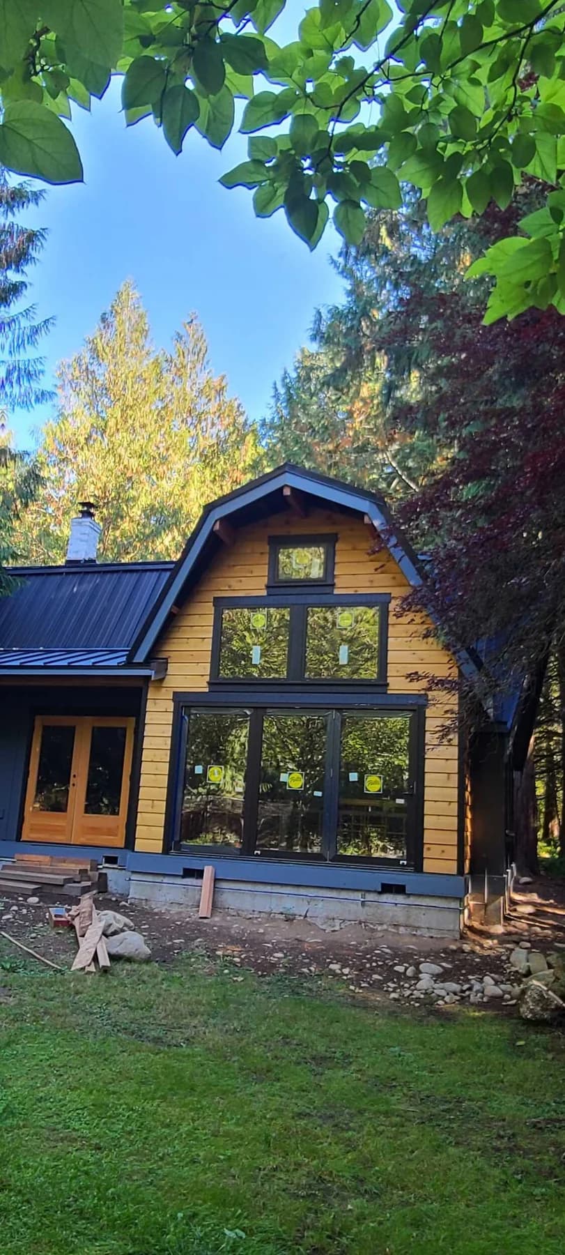 Exterior Finishes — Wood siding, dark window trim, and a metal roof on a custom home under construction