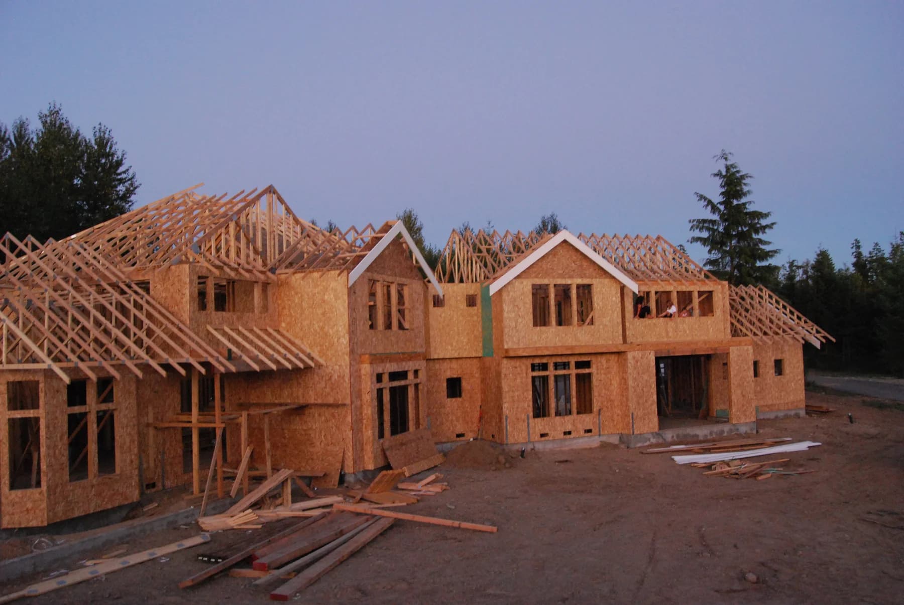 Custom Home Framing — Two-story custom home under construction with exposed roof trusses and sheathed walls