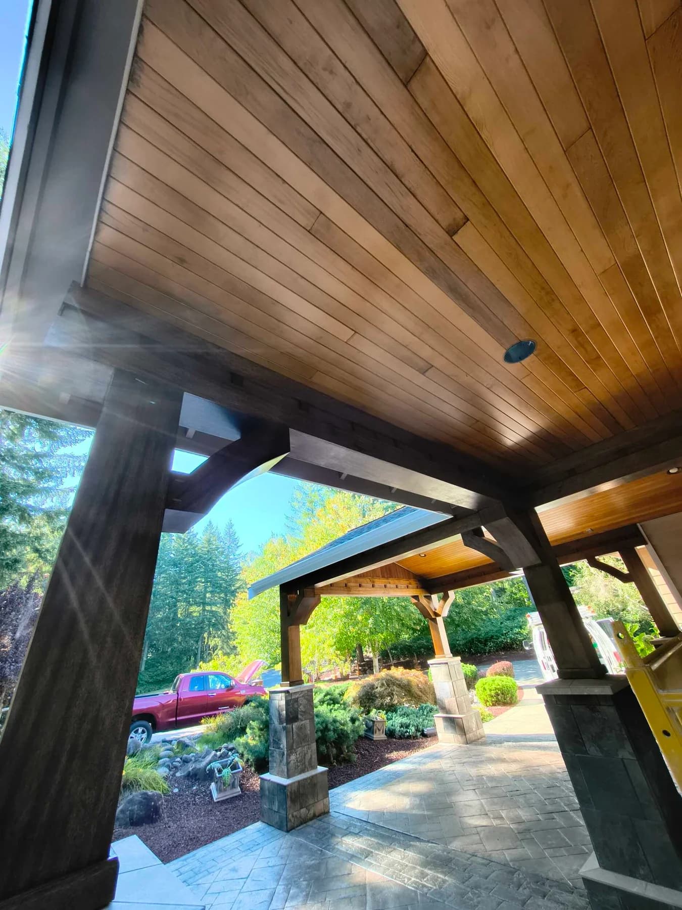 Stained Porch Ceiling — Wood porch ceiling and stained timber beams above stone-clad columns