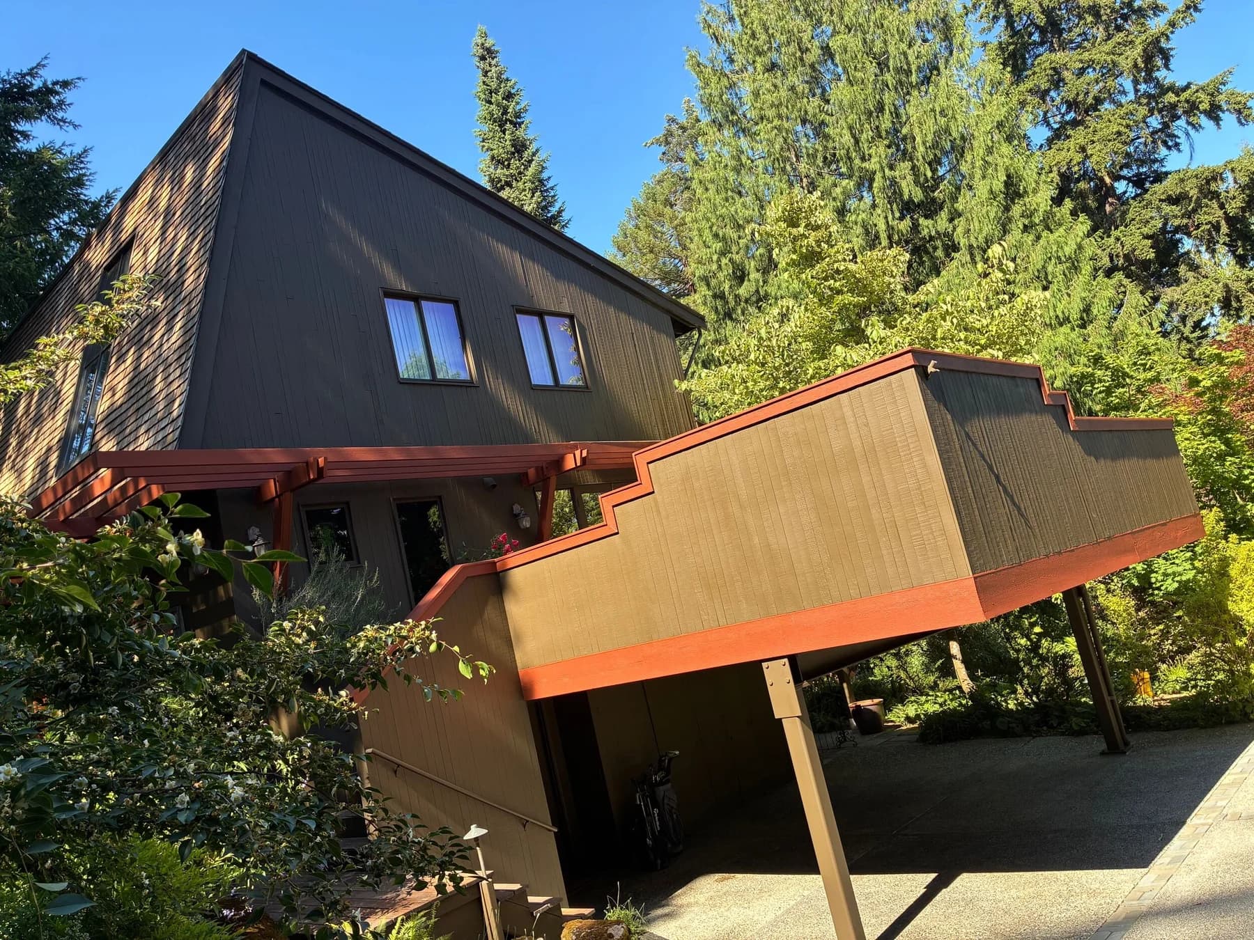 Exterior Siding & Trim — Wooded hillside home with dark siding and contrasting red-brown deck trim