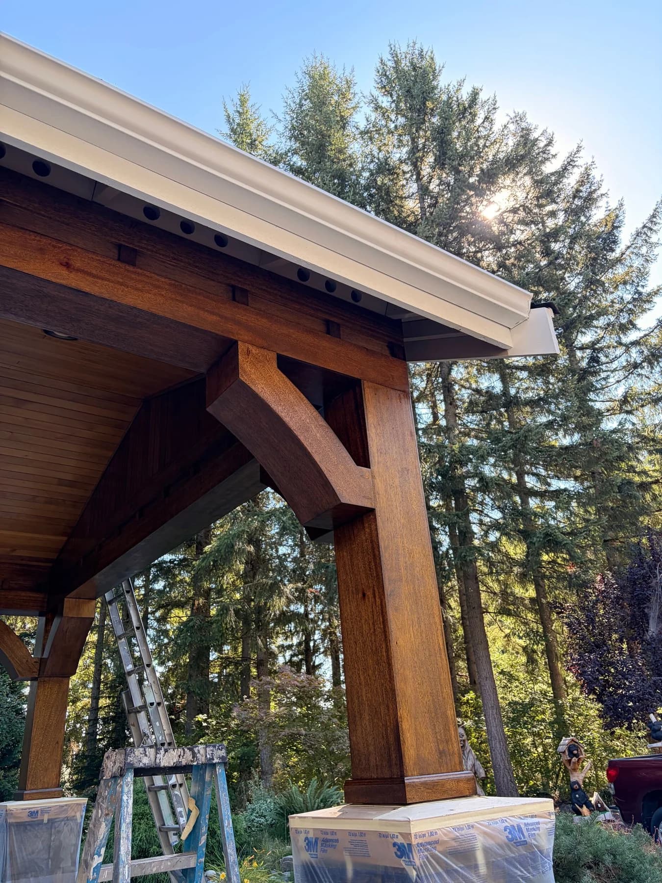 Timber Staining — Stained timber post and brace beneath roof trim with the stone base masked during finishing
