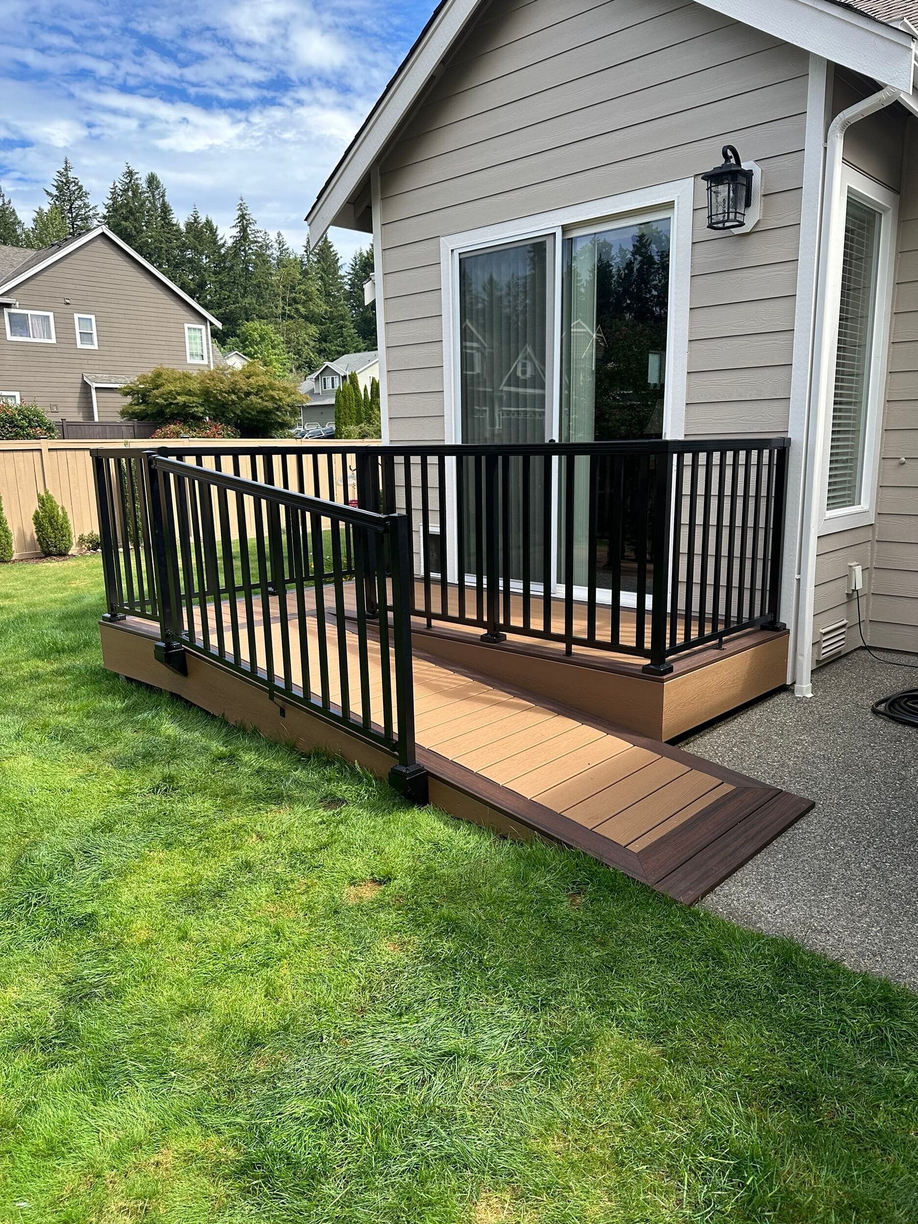Small backyard deck with black railings beside sliding glass doors