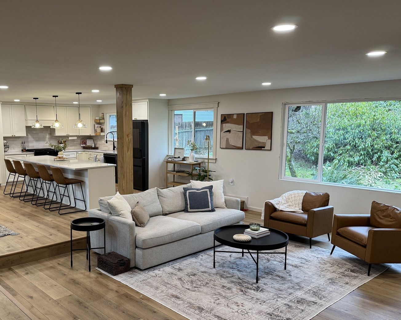 Spacious living room with a couch, armchairs, a rug, and an open kitchen. Spacious living room with a couch, armchairs, a rug, and an open kitchen.