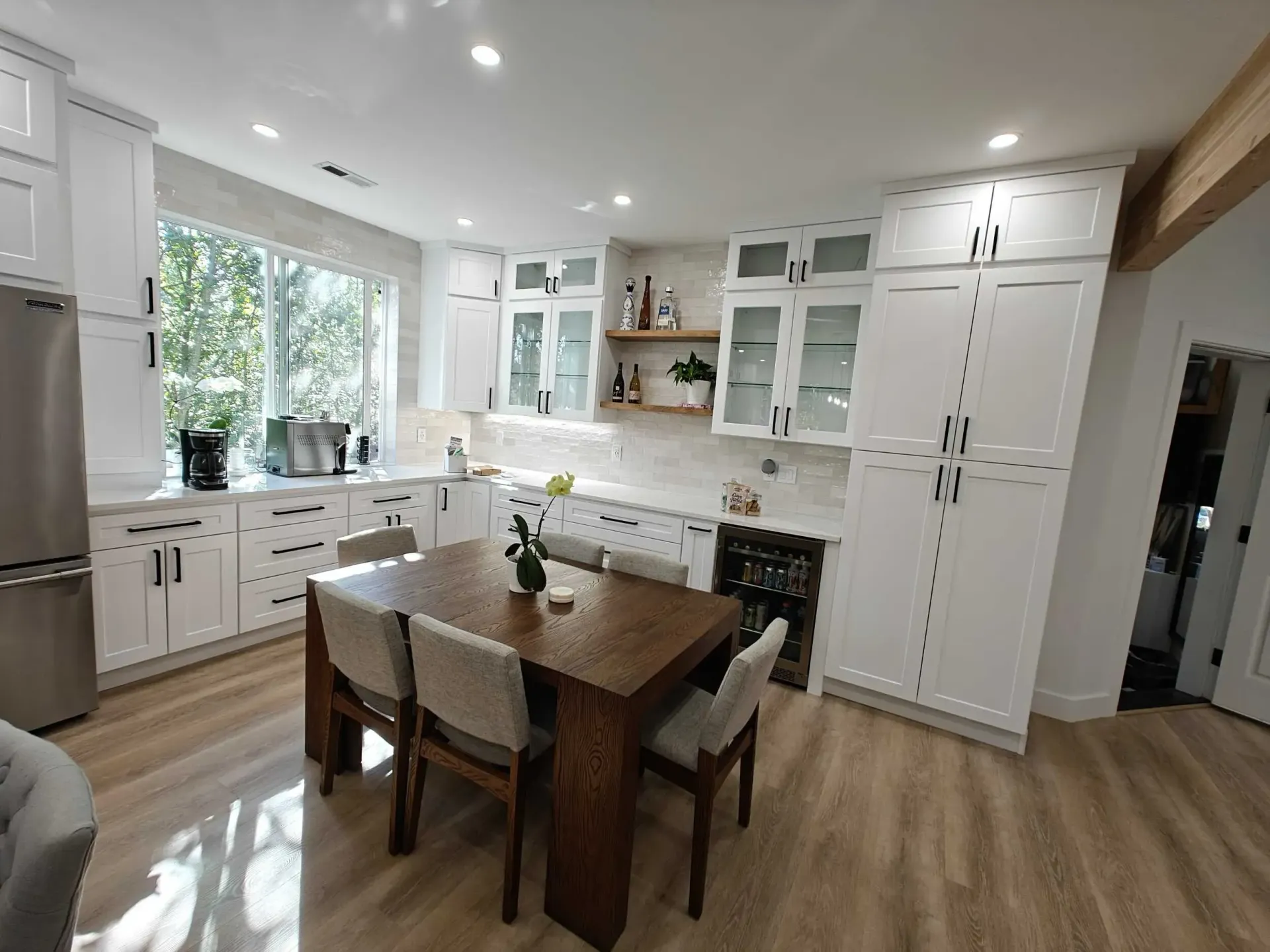 A kitchen with white cabinets and a wooden table and chairs.